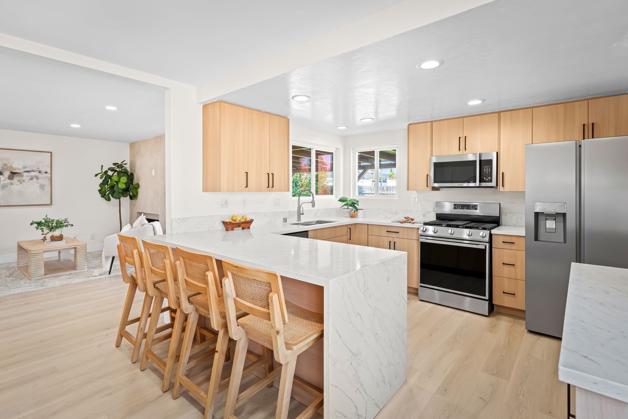 The same kitchen after a full remodel — quartz waterfall island, light cabinetry, new appliances